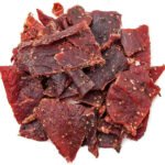 heap of peppered beef jerky on white background from above